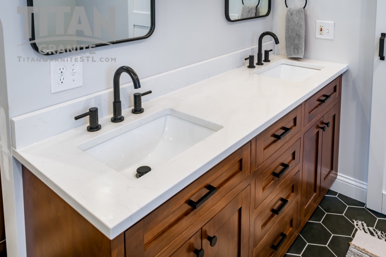 White qaurtz bathroom countertops on double vanity with matte black hardware and wood cabinets.