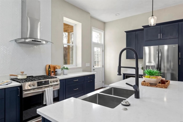 White quartz countertops with navy cabinets and modern stainless steel appliances.