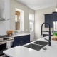 White quartz countertops with navy cabinets and modern stainless steel appliances.