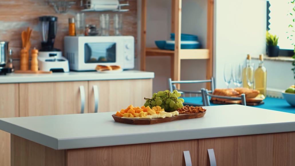 Charcuterie board sitting on gray quartz countertop island with natural brown cabinets