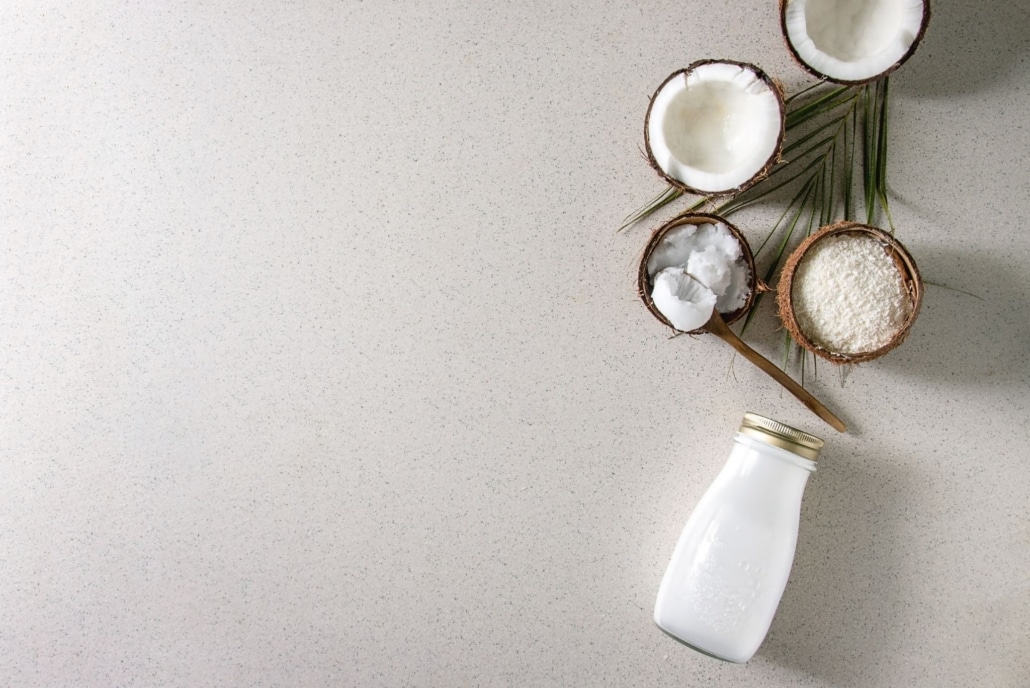 Coconuts and milk sitting on a warm gray speckled quartz countertop